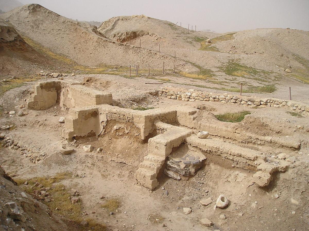 An archaeological site with excavated structures in front of dry hills.