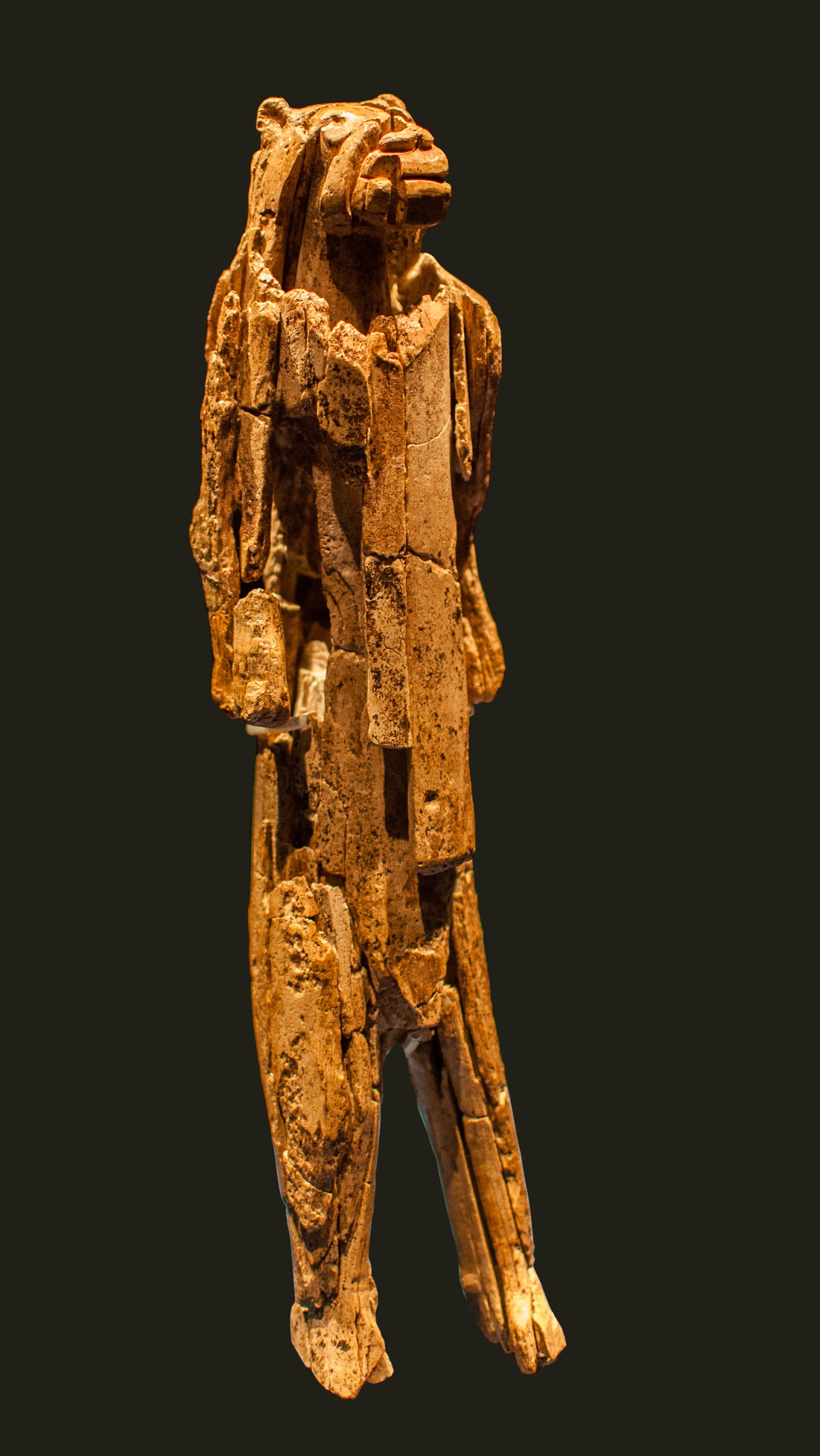 A brown standing statue of a human figure with cat’s head.