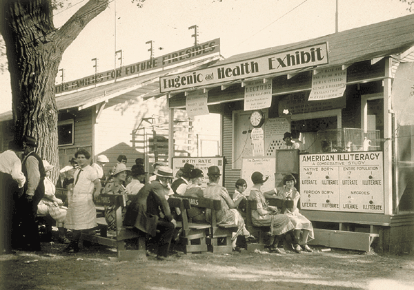 Historic photo. People sit in front of a structure with a “Eugenic and Health Exhibit" banner.