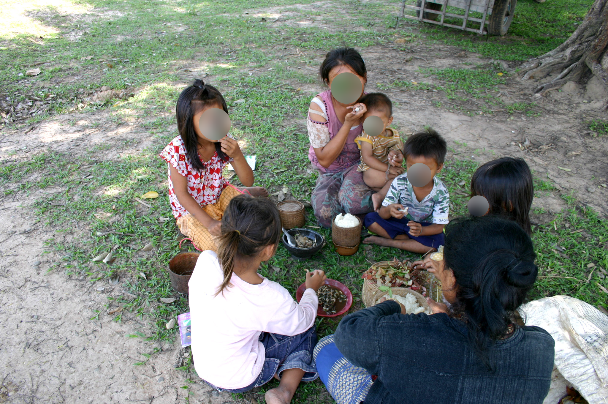 Family sitting on the ground communally eating.